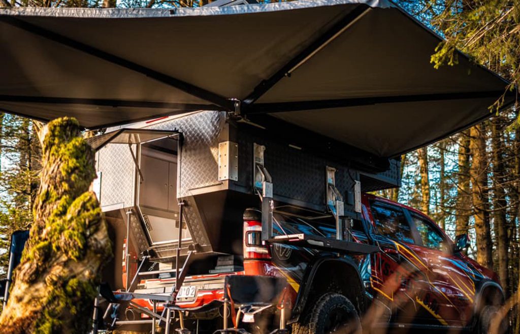 RoadCab fitted onto a Ram 1500 parked in a forest; awning open